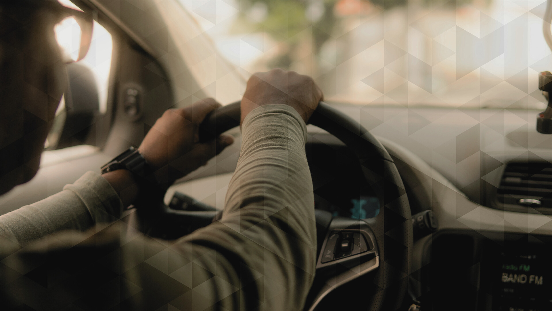 Man driving a car. Image is showing the steering wheel.